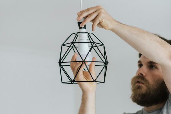 Professional handyman installing modern light fixture with precision and care